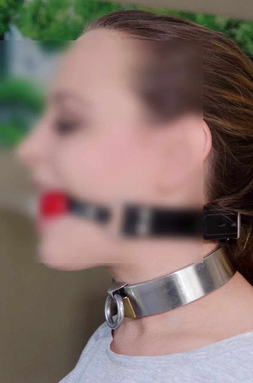 Profile view of a person wearing a metallic neck collar and head strap for a kink dating safety article